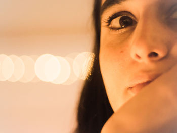 Close-up of young woman in illuminated room