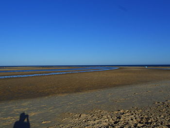 Scenic view of beach against clear blue sky