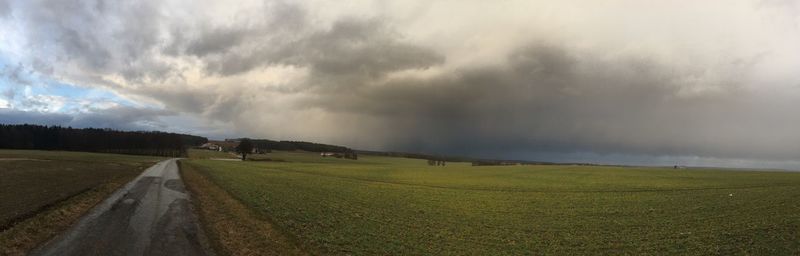 Panoramic view of field against storm clouds