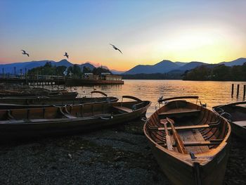 Boats moored at harbor during sunset