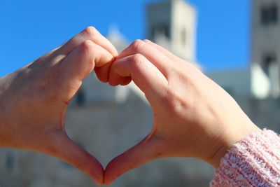 Close-up of girl hands making heart shape in city