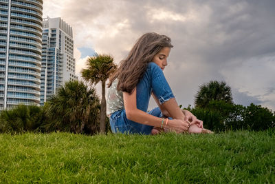 Side view of young woman sitting on field