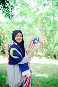 Muslim woman happy holding a malaysian flag. malaysia independence day.