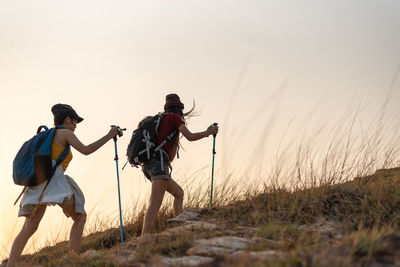 People standing on land against sky during sunset