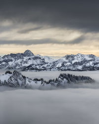 Scenic view of snowcapped mountains against sky during sunset. ground fog shrouds the valley.