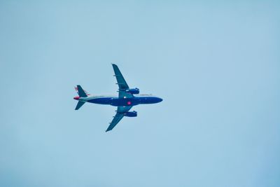 Low angle view of airplane flying against clear blue sky