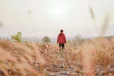 Rear view of man standing on field against sky