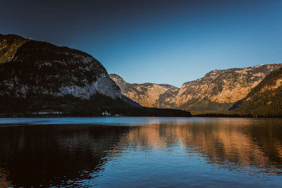 Scenic view of lake and mountains against clear blue sky