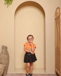 Portrait of young woman standing against wall