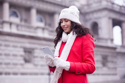 Young woman using mobile phone while standing in winter