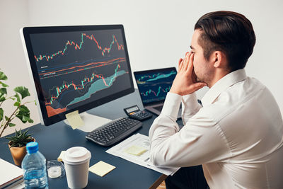 Worried businessman looking at charts stressed by news from stock market. investor lost money online