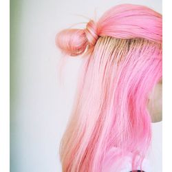 Side view of woman with pink dyed hairstyle standing against white wall