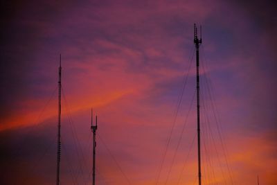 Low angle view of electricity pylon against sky during sunset
