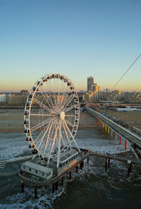 Ferris wheel in city against clear sky