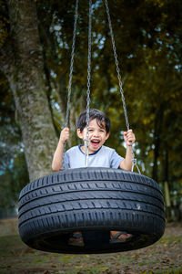 Portrait of smiling boy on swing at playground
