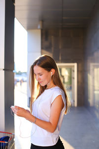 Portrait of young woman standing against wall