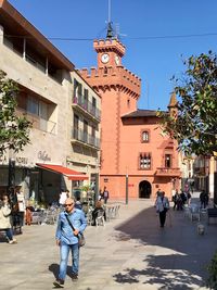 People walking on street amidst buildings in city