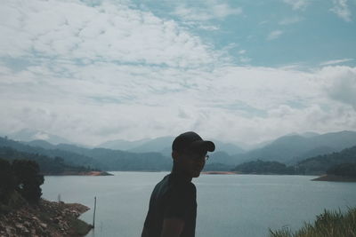 Man standing by lake against sky