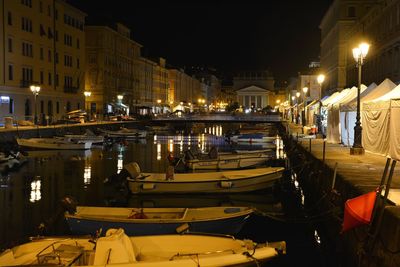 Boats moored at harbor in city at night