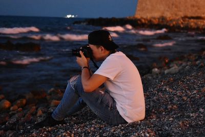 Side view of man photographing at beach