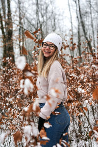 Portrait of young woman standing in winter forest