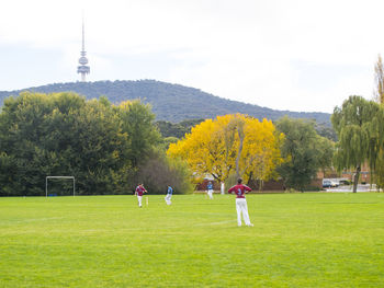 People playing on field against sky