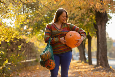 Portrait of young woman standing against trees