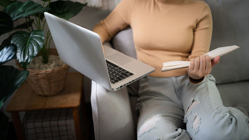 Midsection of woman using laptop