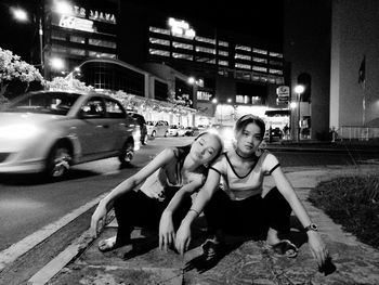 Portrait of young woman sitting in city at night