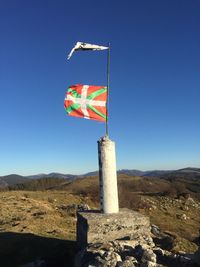 Flag on rock against clear blue sky