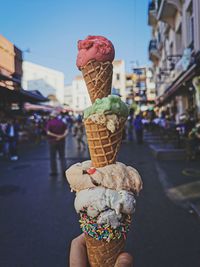 Close-up of ice cream cone against buildings in city