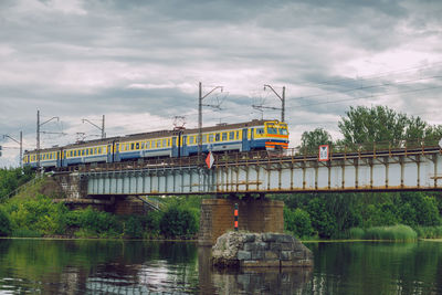 Train on bridge over river against sky