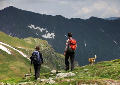 Rear view of hikers with dog standing on mountain