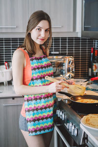 Smiling young woman standing in kitchen at home