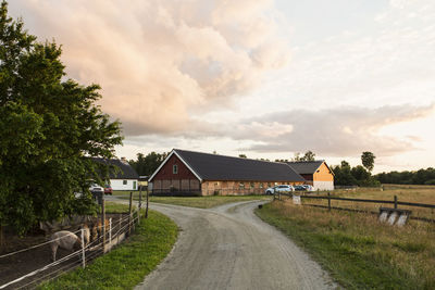 Road leading towards barn against sky at farm