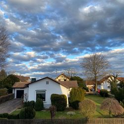 Houses and trees on field against sky