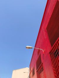 Low angle view of red building against clear blue sky