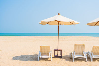 Deck chairs on beach against clear sky