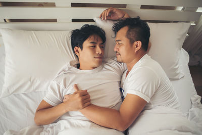 Loving gay couple lying on bed at home