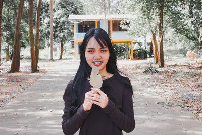 Portrait of smiling young woman standing in park