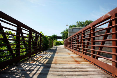 Footbridge amidst trees against clear sky