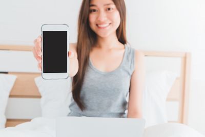 Portrait of young woman using phone at home