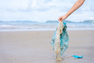 Cropped hand holding garbage on beach