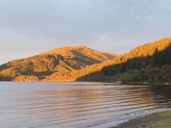 Scenic view of lake by mountain against sky