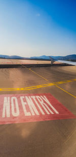 Road sign on airport runway against sky