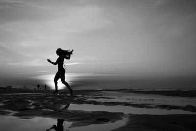 Full length of silhouette person on beach against sky