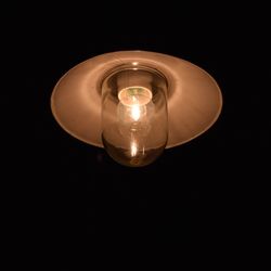 Close-up of light bulb hanging against black background