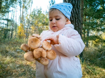 Portrait of cute baby boy holding toy on land