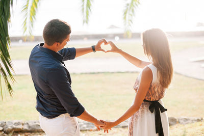 Couple making heart shape while standing at beach