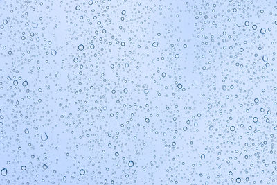 Full frame shot of wet glass against blue sky